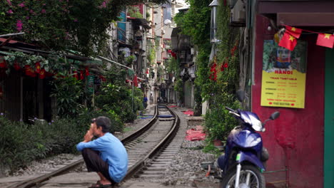 people at train street lined with houses in old quarter, hanoi, vietnam. wide static shot