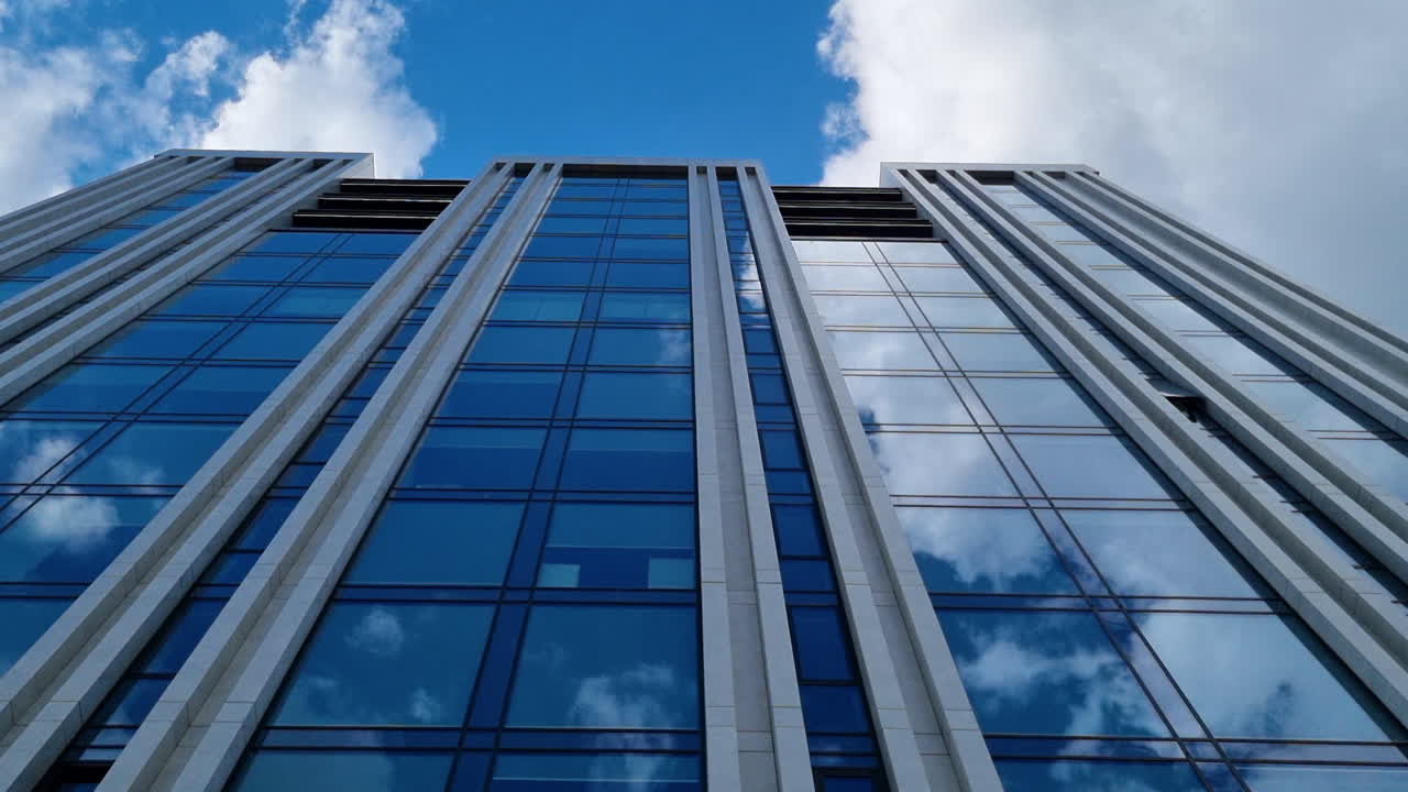 el cielo azul y las nubes se reflejan en las ventanas del moderno edificio de cristal de negocios.