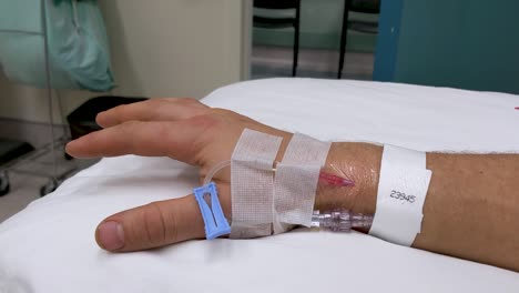 movimientos lentos de la mano de la mano derecha masculina caucásica irreconocible en un escenario médico con iv en la muñeca