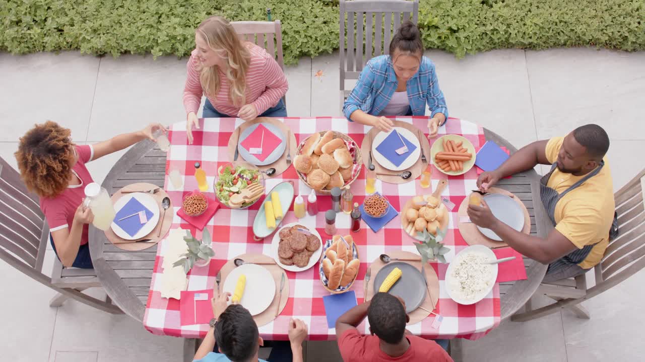 grupo feliz y diverso de amigos comiendo y hablando en la mesa de la cena en el jardín, cámara lenta