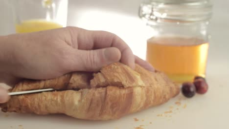 Croissant-Recién-Horneado-Abierto-Con-Miel-Y-Fondo-De-Jugo-De-Naranja-Primer-Plano