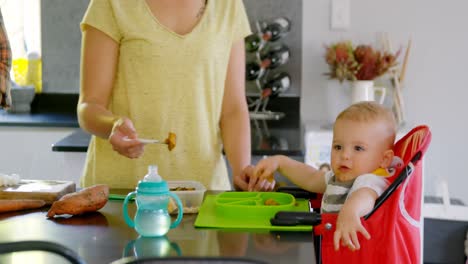 madre preparando el desayuno para su bebé en la cocina 4k