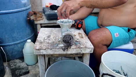 man hands make chum, grinds bait fishes use drill to speed up manual fishing work