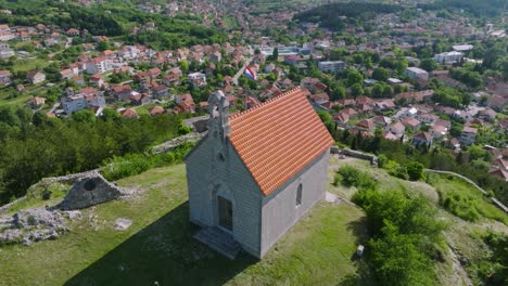 Restored-old-medieval-chapel-over-Croatian-town-Sinj-on-a-summer-day,-aerial