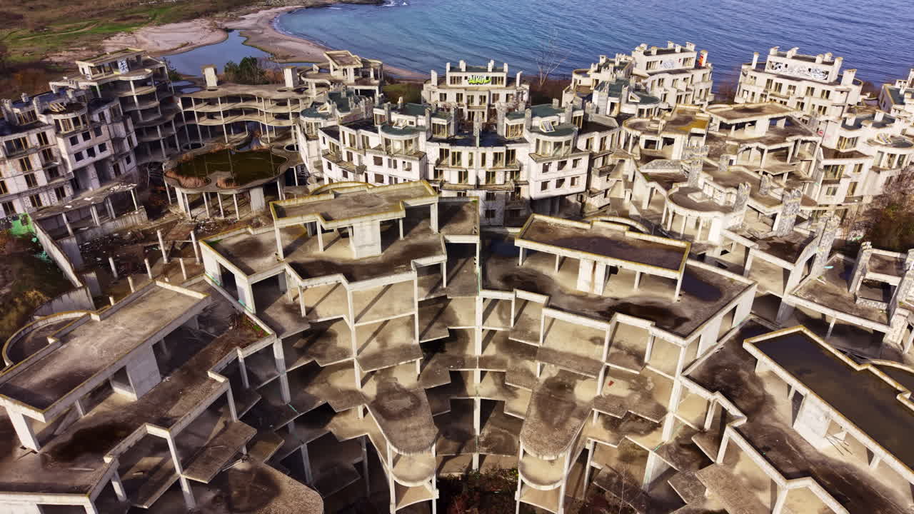 Meraviglie architettoniche abbandonate si ergono dalla costa, sussurrando storie di sogni e desolazione vicino al mare tranquillo.