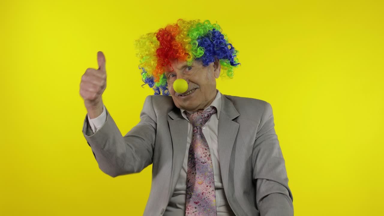 anciano payaso hombre de negocios independiente en peluca muestra el pulgar hacia arriba. halloween