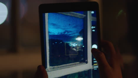 young-caucasian-woman-using-tablet-computer-taking-photo-at-night-enjoying-photographing-view-sharing-lifestyle-on-social-media-in-home-apartment-close-up-portable-technology-close-up