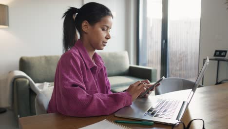 woman browsing phone while working on computer