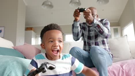 african american grandfather and grandson having fun, playing video game, slow motion