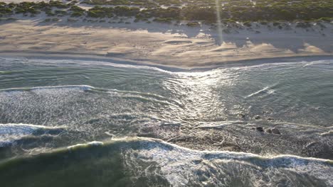 Drohnenluftaufnahme-Nach-Rechts,-Die-Sanddünen-Und-Einen-Unberührten-Strand-Bei-Sonnenaufgang-Zeigt