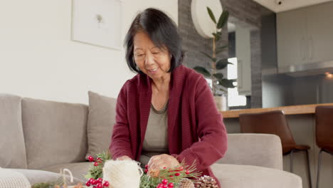 senior asian woman crafting christmas decorations at home, enjoying festive solitude