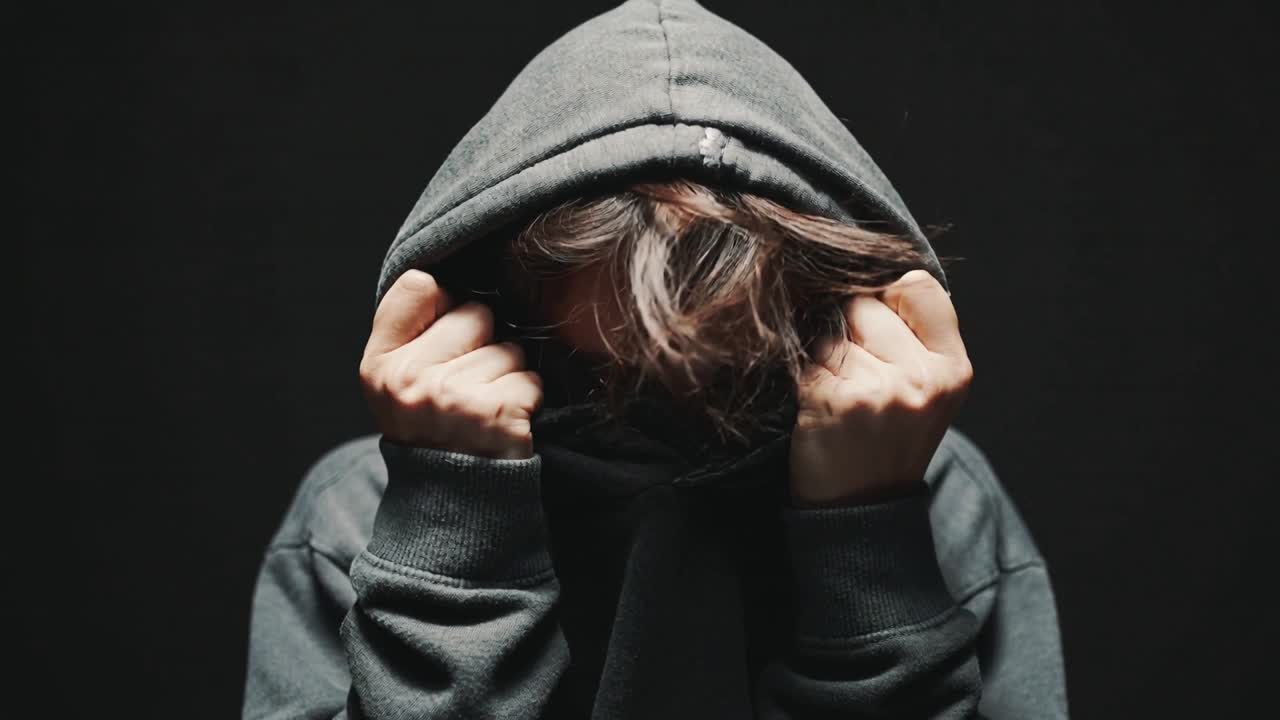 Trækker hætten op, da spotlight tændes, mandlig person skjuler ansigtet, mørkegrå hættetrøje, hår