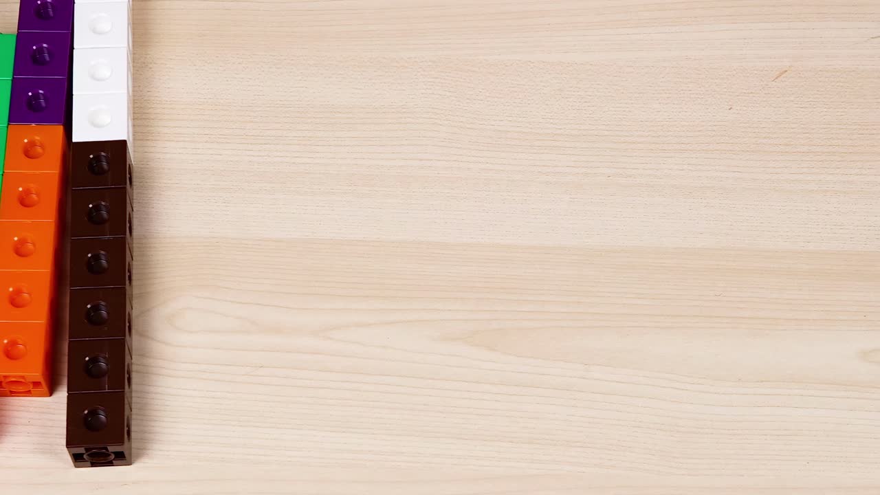 Hands precisely align colorful linking cubes in a vertical sequence on a wooden table.