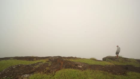 Mann-Am-Rand-Der-Klippe-Vor-Nebligem-Himmel