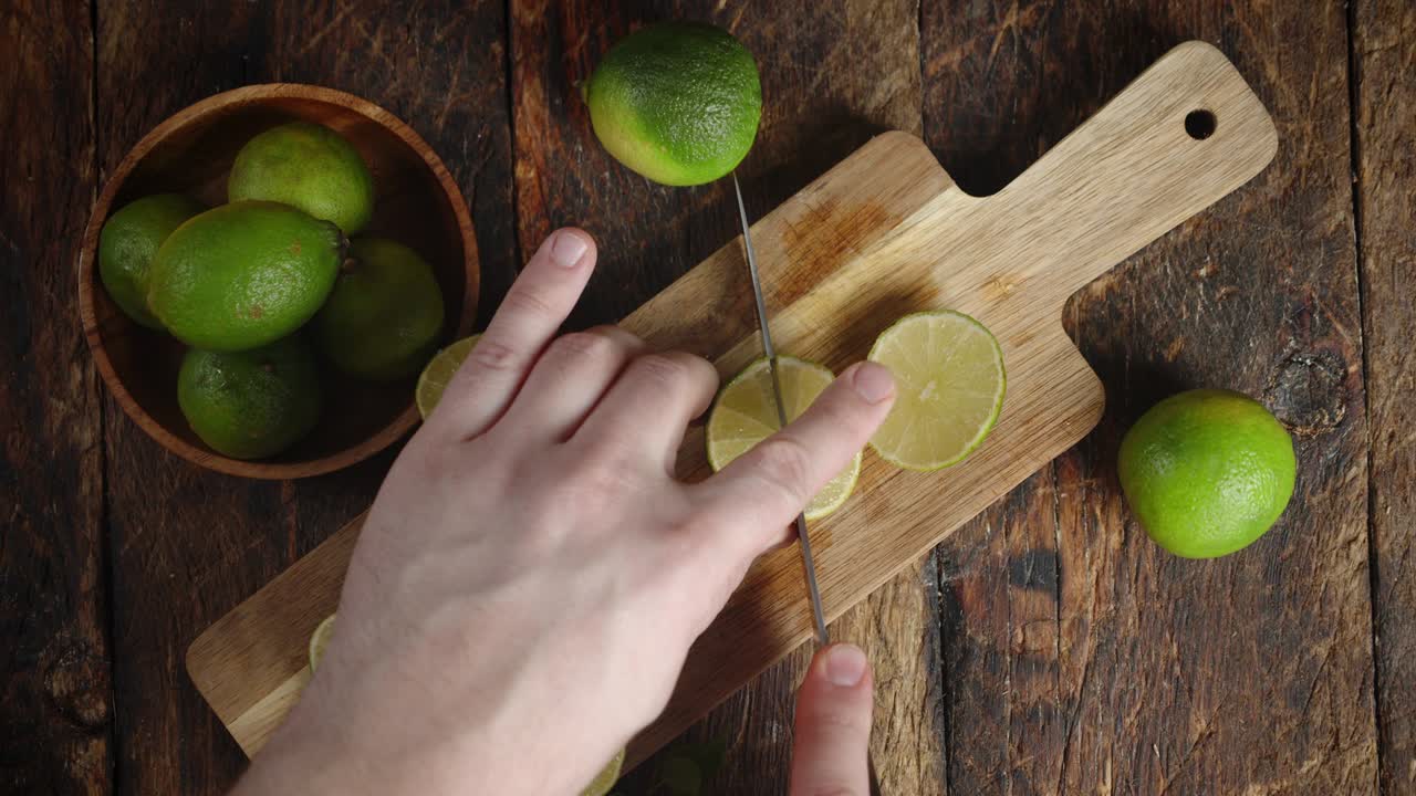 las manos de los hombres cortan cal en la tabla de cortar.