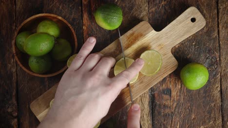 las manos de los hombres cortan cal en la tabla de cortar.