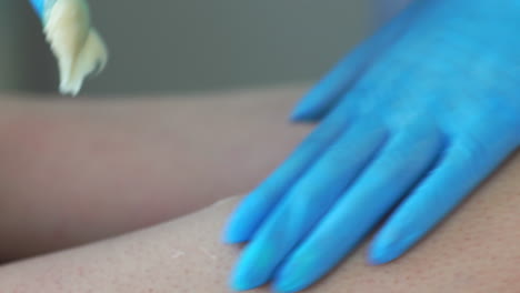 primer plano de la mano del maestro de la depilación eliminar pequeños pelos con una técnica especial de azúcar haciendo sacudidas afiladas con la mano