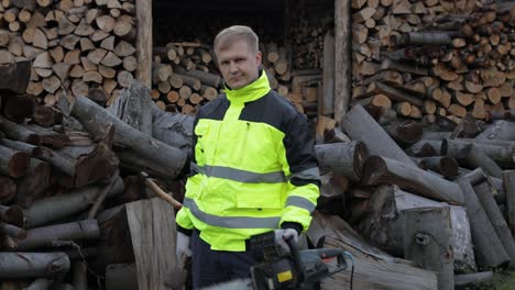 Lumberjack-worker.-Man-woodcutter-holds-big-axe-and-electric-chainsaw-on-his-hands.-Firewood