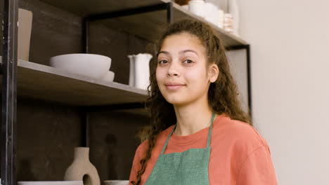 portrait of a beautiful young female clerk smiling and looking at the camera while working in the pottery shop