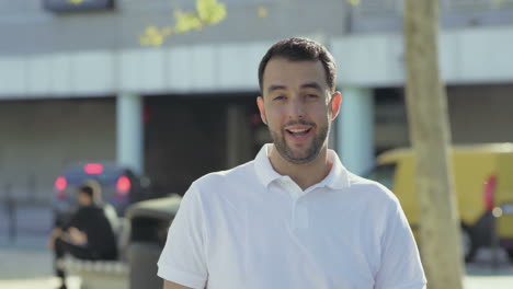 smiling young man with hand on chin looking at camera.