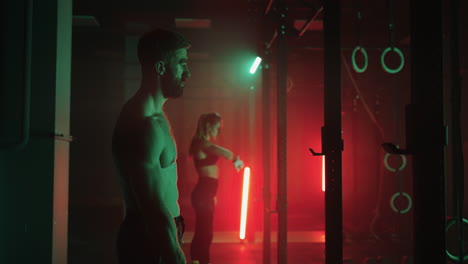 brawny man and slender woman are training in gym sporty people are standing in front of crossbar