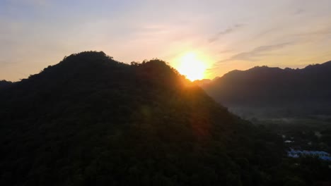 4k drone footage revealing a beautiful sunset over a vast valley from behind a mountain in khao yai, thailand