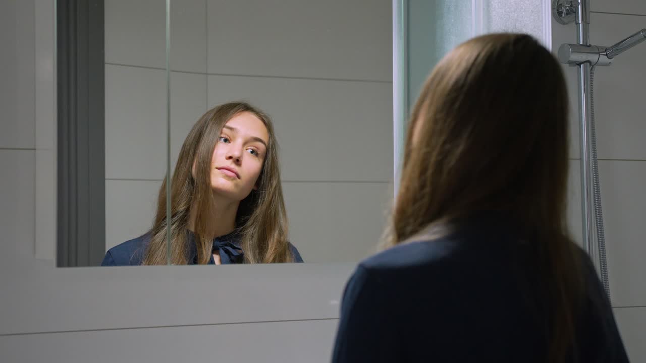 Giovane donna che si guarda allo specchio del bagno, al rallentatore.