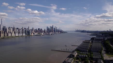 aerial view overlooking the west new york coastline with manhattan background, in sunny new jersey, usa - rotating, pull back, drone shot