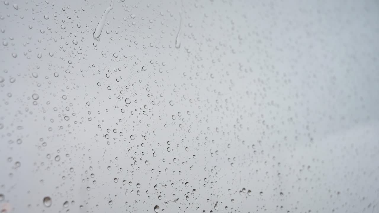 se ve a través de un vidrio de la ventana una foto cercana en cámara lenta de las fuertes gotas de lluvia