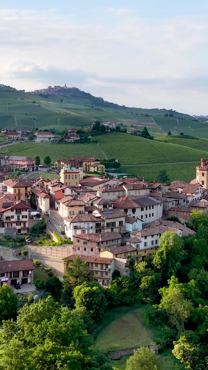 Un lento zoom all'indietro rivela un borgo storico italiano annidato tra dolci colline di vigneti.