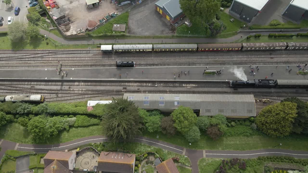 Aerial view of the Minehead steam railway station England's longest heritage line, running 20 miles between Minehead and Bishops Lydeard. Drone moving right following one of steam train into station