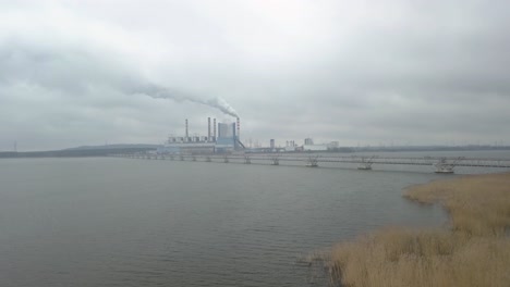 drone fly above river with power plant industry scenario landscape at distance under clouds dramatic sky