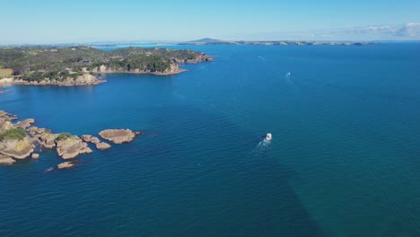 Barcos-Navegando-Por-La-Bahía-De-Oneroa-Con-Afloramientos-Rocosos-En-Auckland,-Nueva-Zelanda