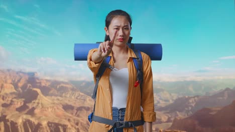 asian female hiker with mountaineering backpack showing no gesture with index finger while traveling at the top of mountain