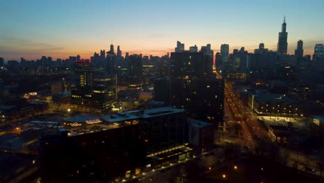 a captivating drone aerial view panning right of chicago at dusk showcasing illuminated skyscrapers against the darkening sky the golden hues of sunset paint are highlighting architectural marvels