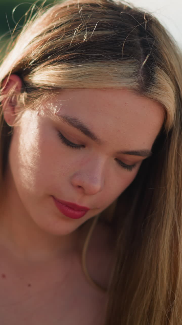 그녀가 아래로 초점을 맞추면서 깊은 생각에 빠진 것처럼 보이는 사려 깊은 여인, 배경에는 초록색과 흐릿한 램프 기둥이 있습니다.