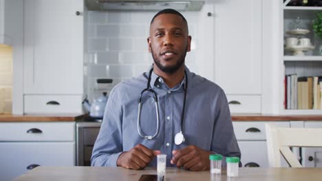 portrait of african american doctor talking while having a video call at home