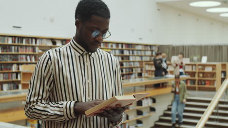 african man reading book in library