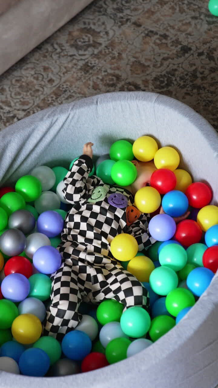 Funny child playing in colorful balls. Playful small boy having activities.