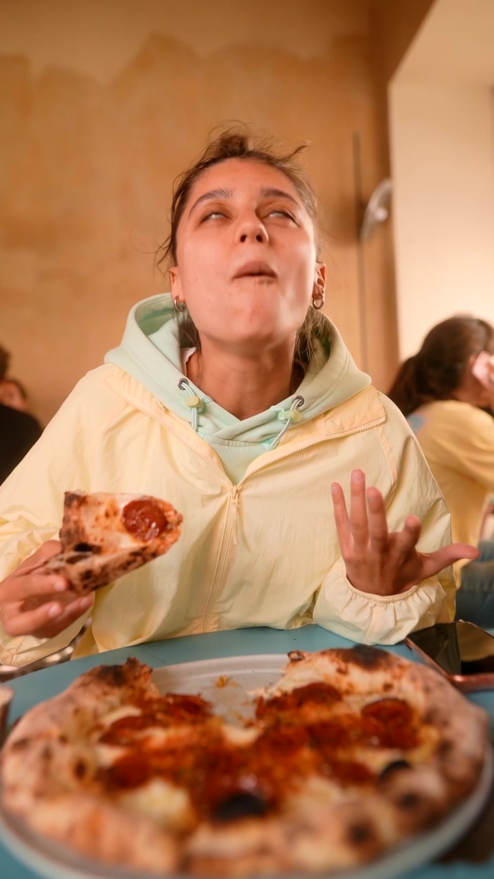 Giovane donna che mangia pizza al salamino piccante in un ristorante