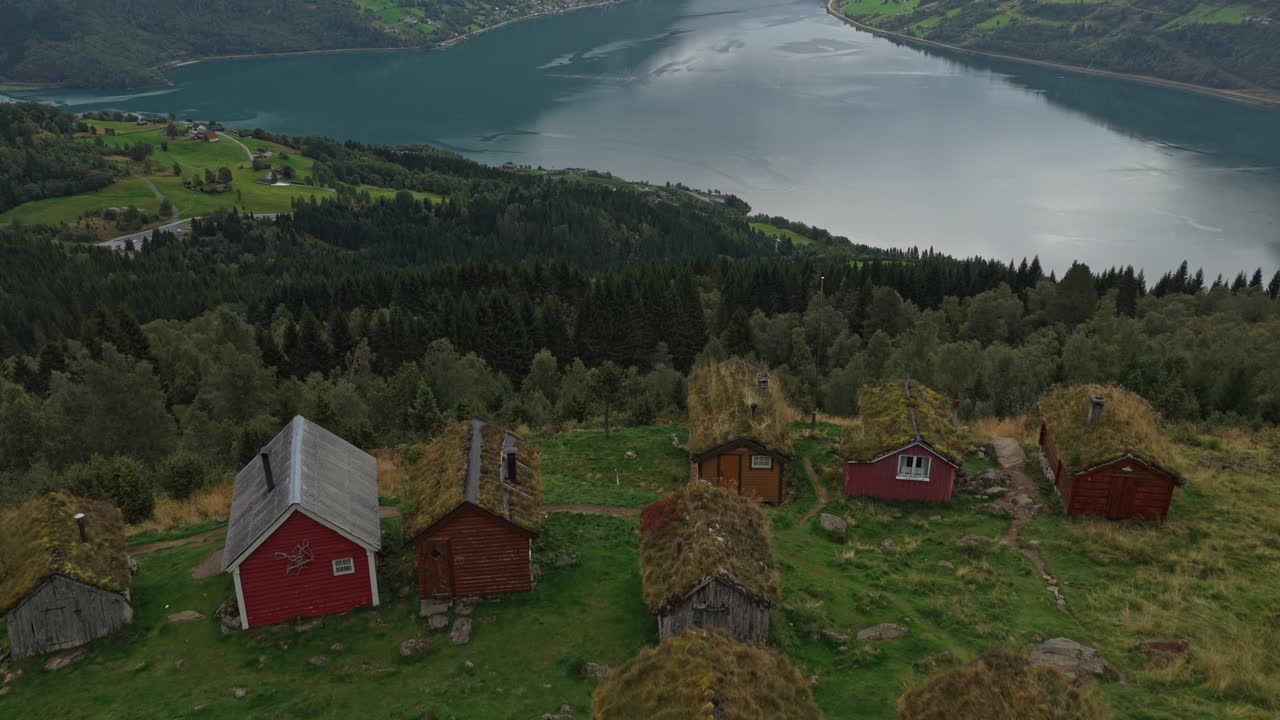Dronebilde av trehytter på grønne skråninger i Rakssetra, Norge.