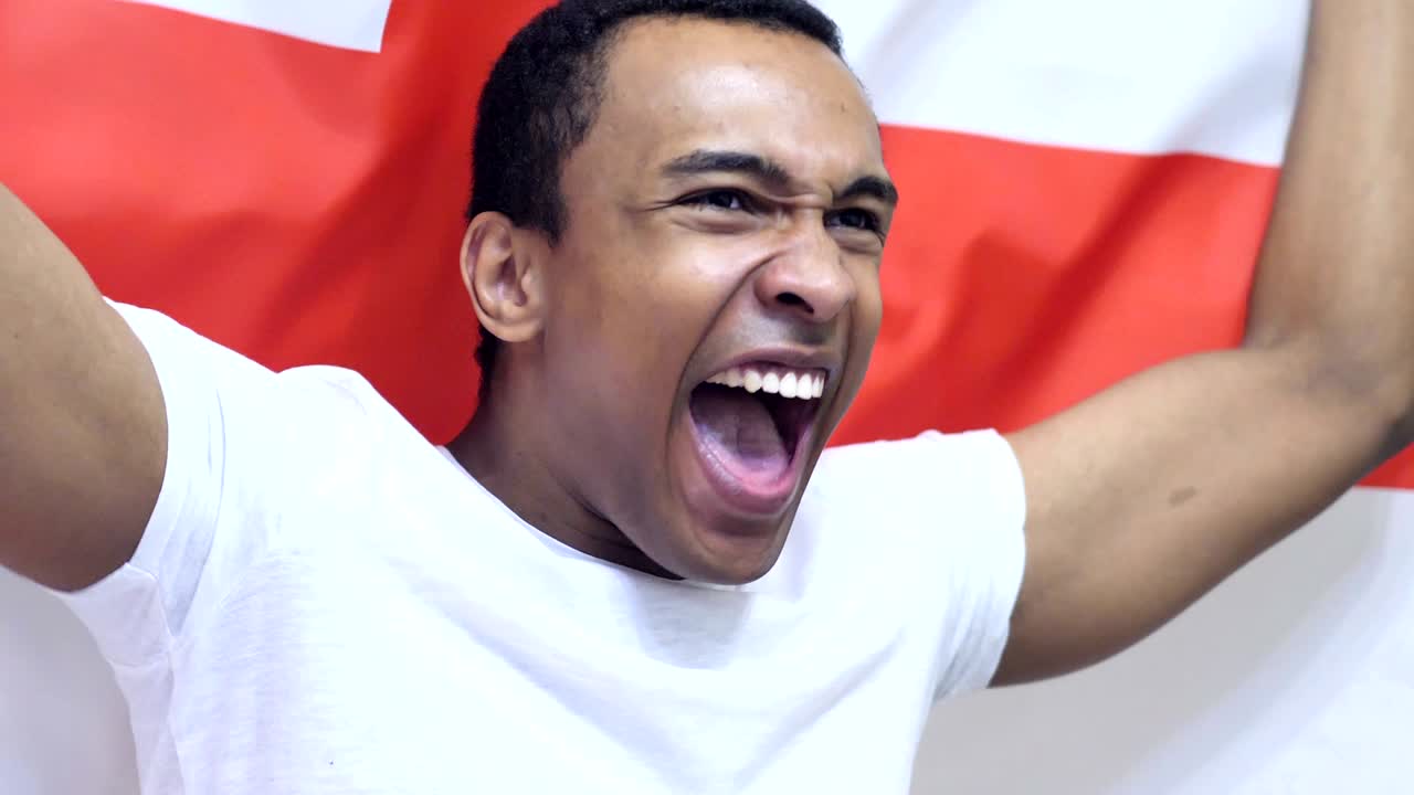 fanático inglés celebrando mientras sostiene la bandera de inglaterra en cámara lenta