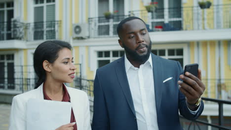 serious mixed race business couple having video chat on mobile phone outdoors.