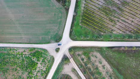 Vista-Aérea-De-Un-Automóvil-Que-Se-Mueve-En-Una-Carretera-Vacía-En-Los-Campos-De-Otoño-En-Toscana,-Italia