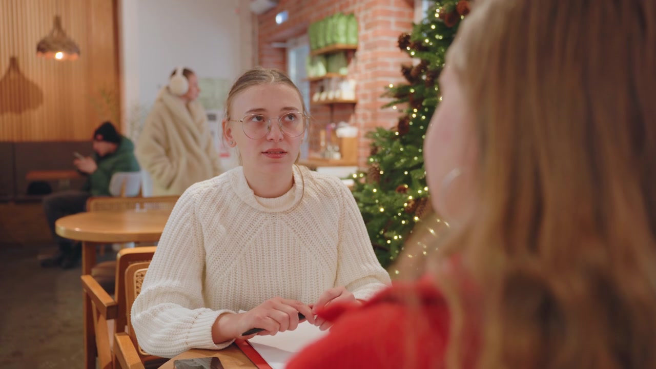 居心地の良いクリスマスカフェで会話している若い女性。