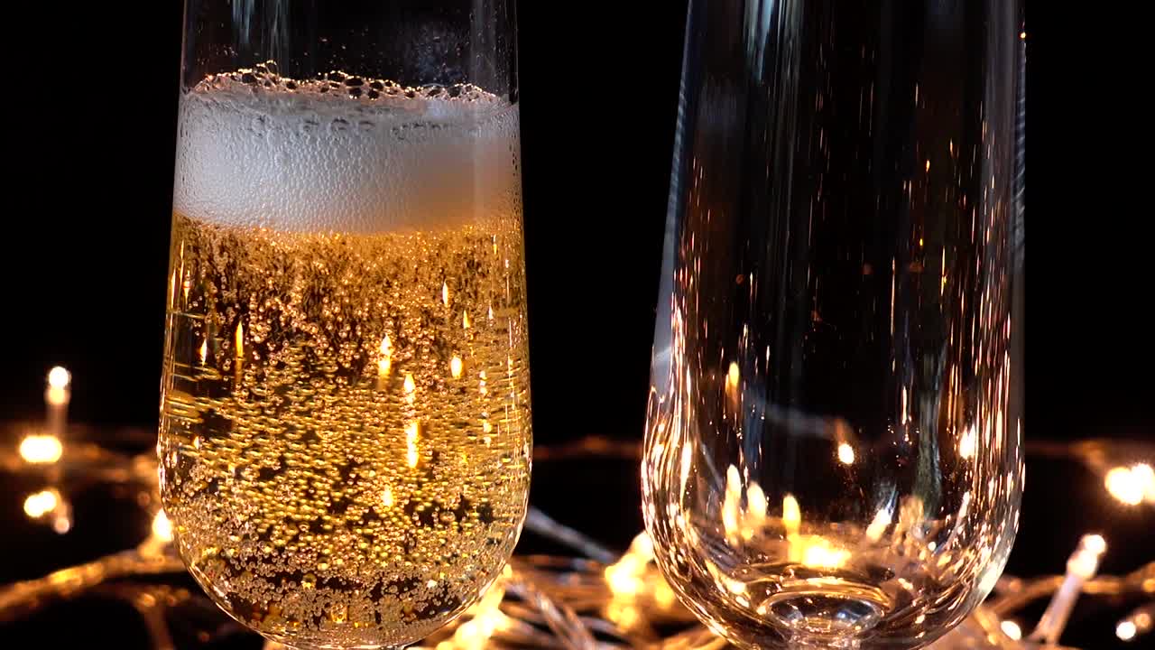 Calici da champagne e una rosa sullo sfondo di ghirlande luminose