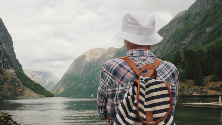 Ein Tourist mit Rucksack auf dem Rücken bewundert den malerischen Fjord in Norwegen Aktiver Lebensstil und Tourismus