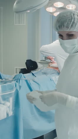 la enfermera organiza el trabajo durante la operación cardíaca. el trabajador médico trae las herramientas quirúrgicas necesarias para garantizar el alcance de la cirugía de derivación de la arteria coronaria