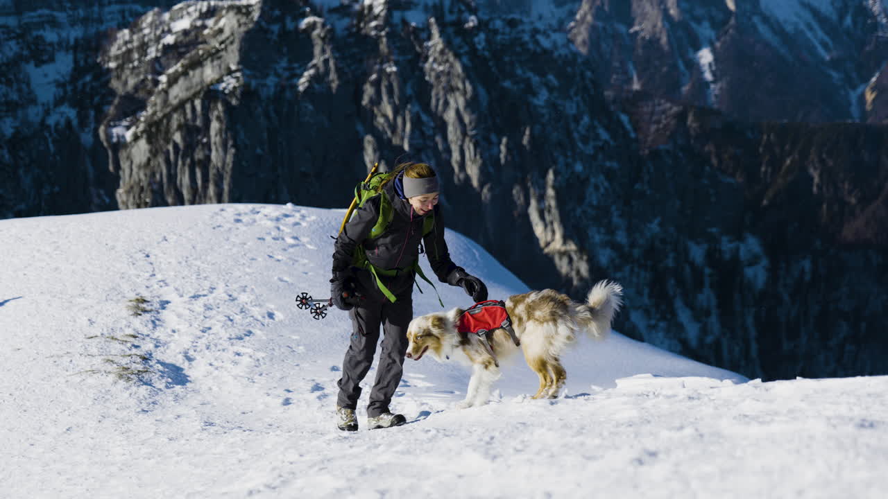 Woman and Dog Hiking in Snowy Mountains
