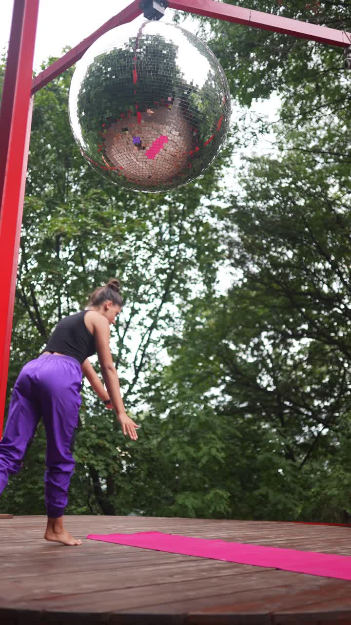 mujer haciendo un handstand afuera cerca de una pelota de discoteca